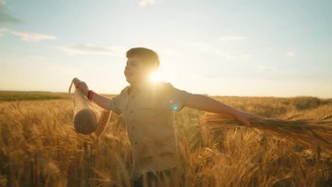 快乐的胖乎乎的男孩在金色的田野上奔跑，日落时间快乐的孩子的肖像，慢动作拍摄