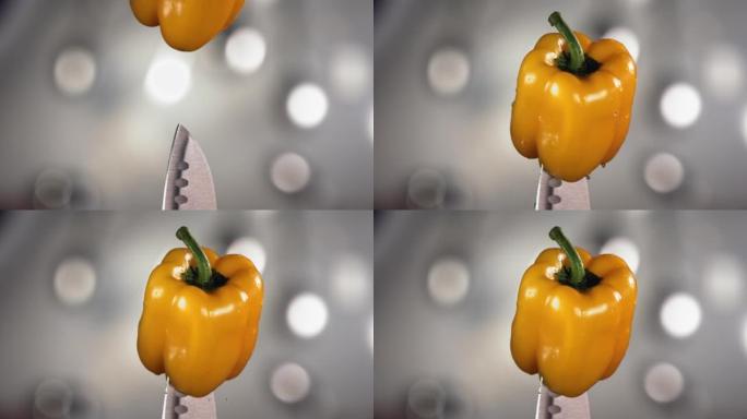 新鲜的黄色甜椒掉落，水滴在刀子上。慢动作。