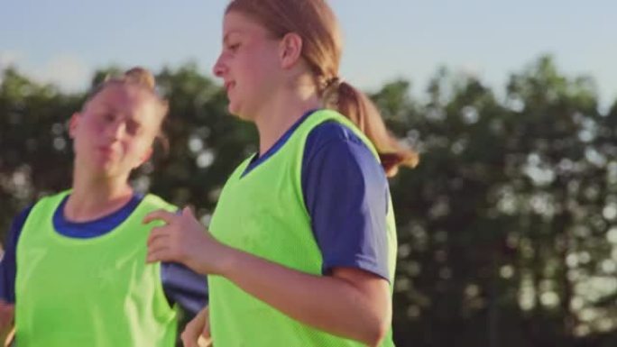 TS年轻的女子足球队在练习中在运动场上奔跑