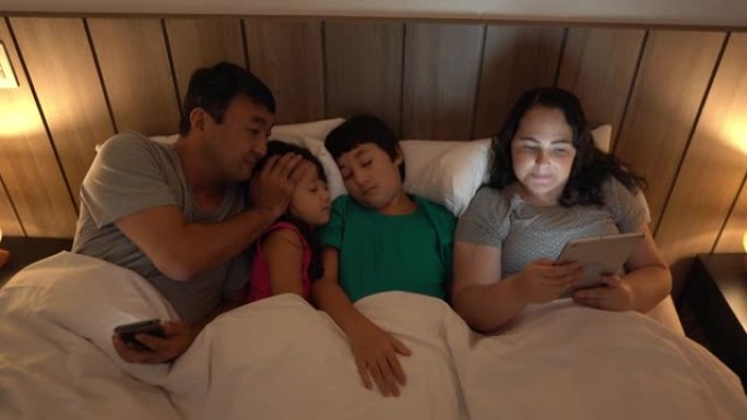 孩子在家睡觉时，父母在床上使用便携式信息设备