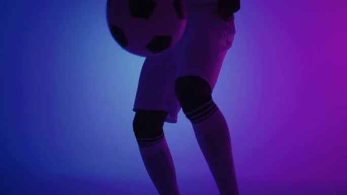 足球运动员在工作室里用蓝色和紫色和双脚特写玩球keepie-uppie