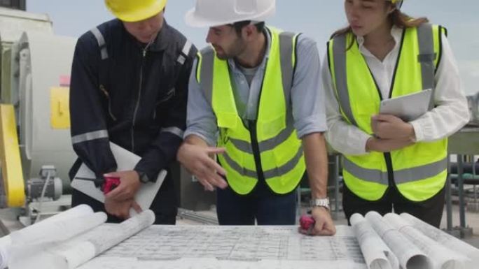 项目工程师和技术员团队穿着安全背心和头盔集中讨论屋顶施工现场的工作，工程师团队一起工作