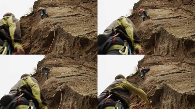 两个人在干燥的山沟攀岩上山。专注于他的下一步行动。