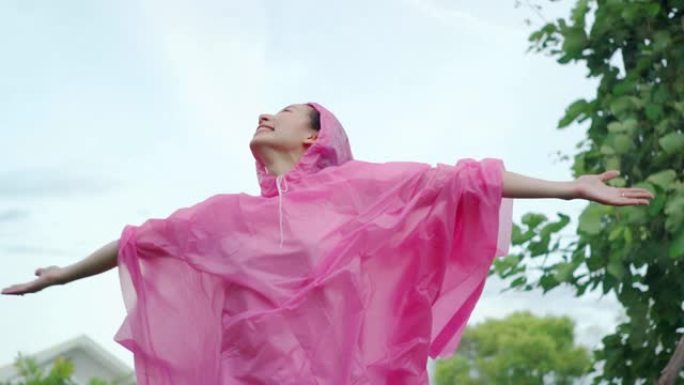 穿着粉红色雨衣的年轻美丽幸福的女人享受着rian的慢动作。