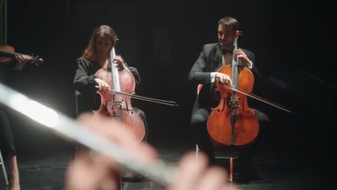 管弦乐队在爱乐大厅排练，大提琴演奏者在演奏音乐，弦乐器