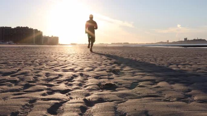 男子在日出时沿着空旷的海滩奔跑