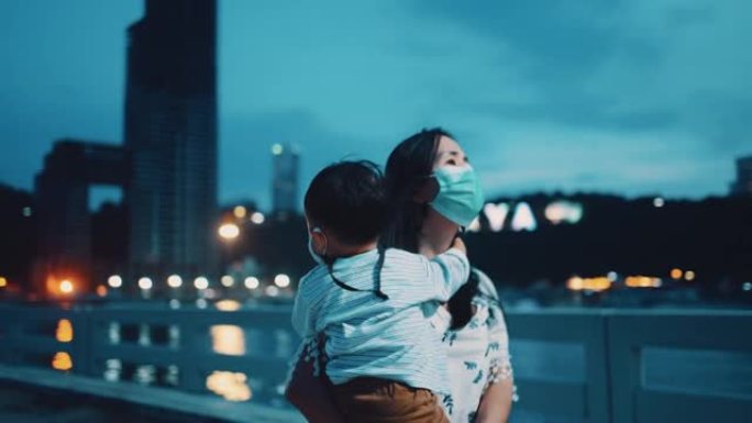 年轻的母亲在泰国黄昏时抱着儿子