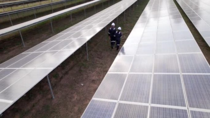 从阳光下鸟瞰太阳能电池的技术工程师，检查太阳能发电场的太阳能电池板。