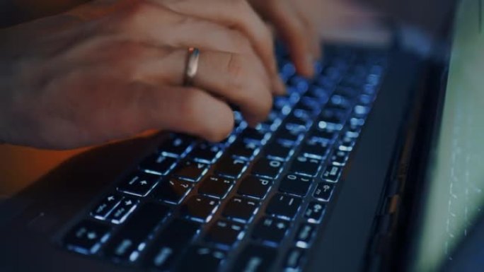 男人正在笔记本电脑的键盘上键入消息和文本，手指的特写视图，照明键