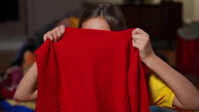 可爱的有趣的少女躲在红色毛衣上看着相机。相当放松的无忧无虑的高加索黑发少年的肖像，棕色的眼睛在室内摆