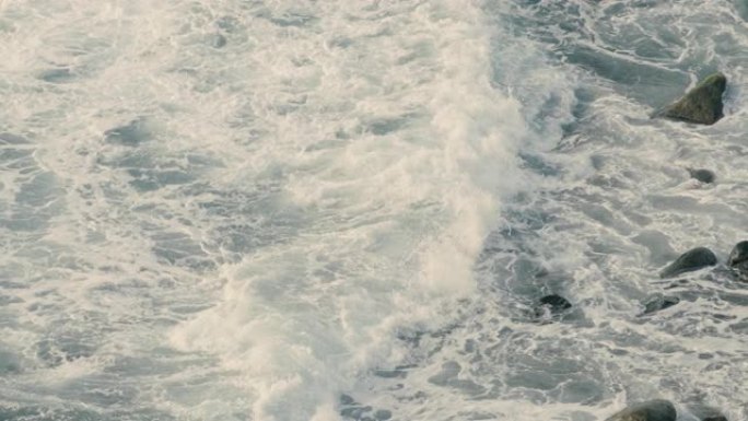空中无人机拍摄的海浪在岩石海滩上坠毁