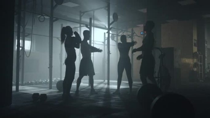 一群运动的人在健身房训练，两个强壮的男人和两个迷人的女人正在温暖肌肉