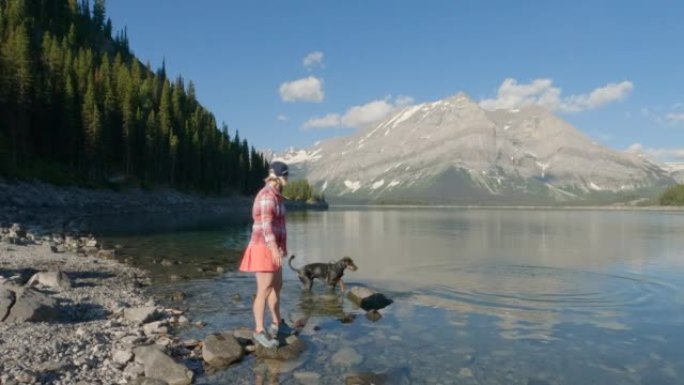 女人在山湖畔享受与peg狗的时光