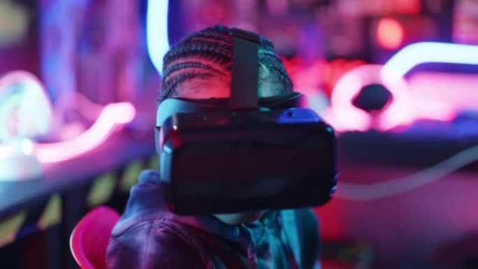 非洲男孩戴着VR或虚拟现实眼镜，头戴式耳机并在游戏室玩电子游戏。