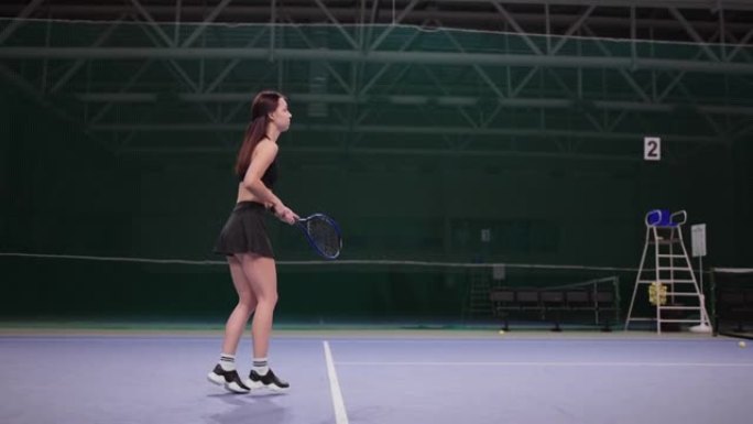 年轻女子在室内球场打网球，用网球拍击球，在区域内奔跑，慢动作