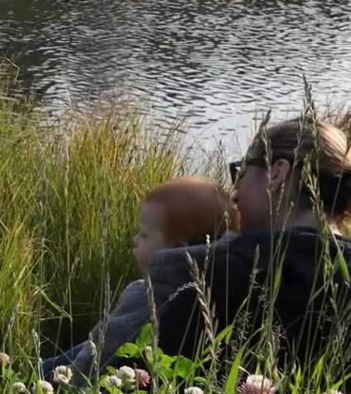 母亲和小儿子在creek edge放松，看着鸭子
