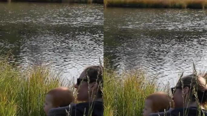 母亲和小儿子在creek edge放松，看着鸭子