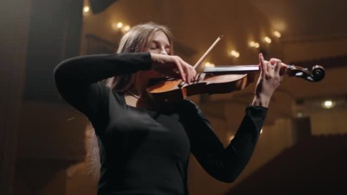 年轻的女音乐家在音乐厅拉小提琴，用小提琴描绘女人