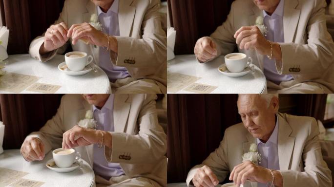 年迈英俊的老人在餐桌上加糖咖啡