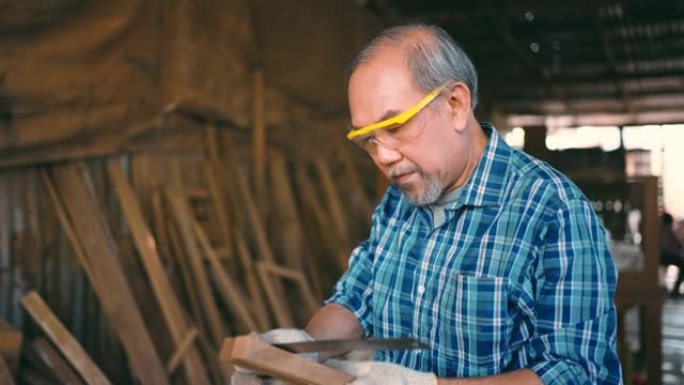 活跃的老年人木匠在闲暇时间用木头工作。