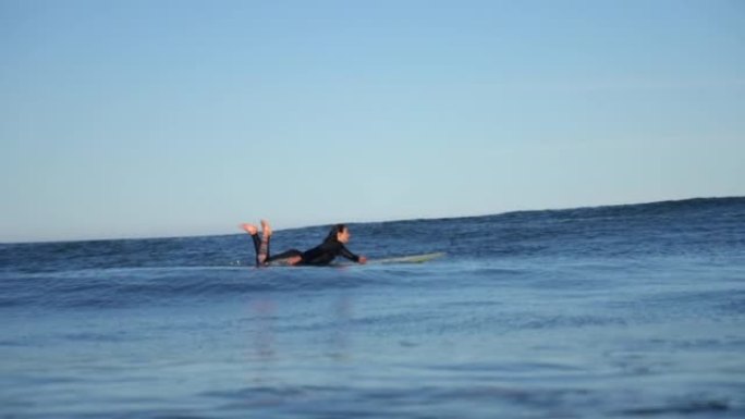 女人在海浪上冲浪，一边微笑一边欣赏风景
