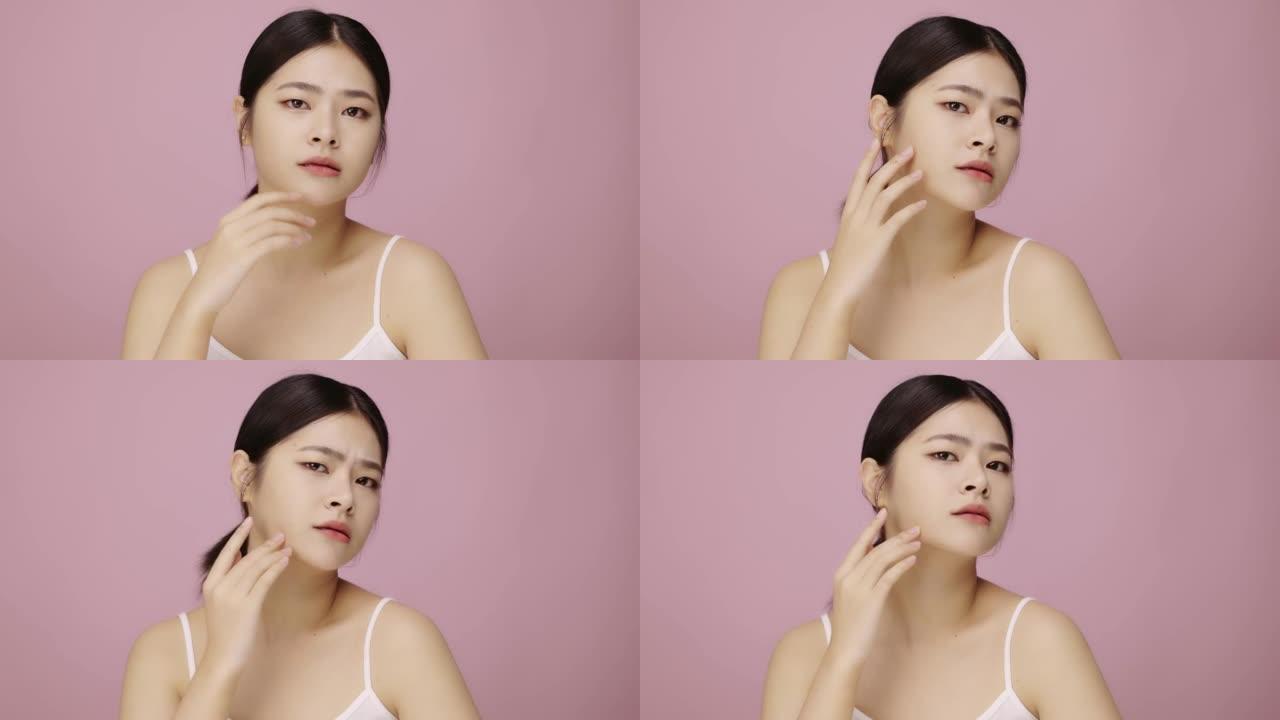 年轻的亚洲女性担心粉红色背景下的面部皮肤问题。