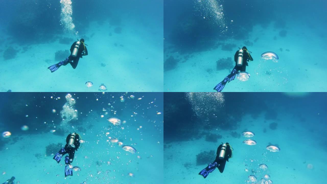 探索红海的潜水点。潜水员向海底下降，气泡接触相机镜头