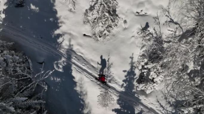 一名男子穿越雪山树木的空中无人机拍摄