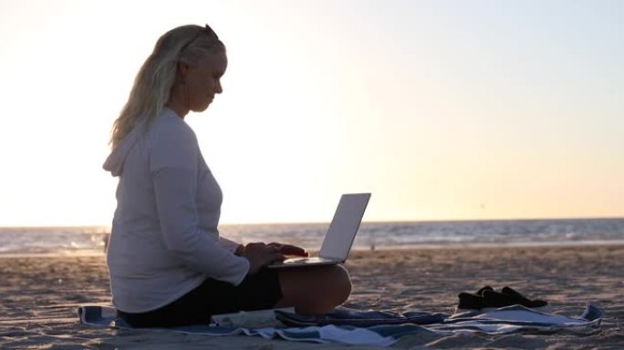 女人在安静的海滩上使用笔记本电脑