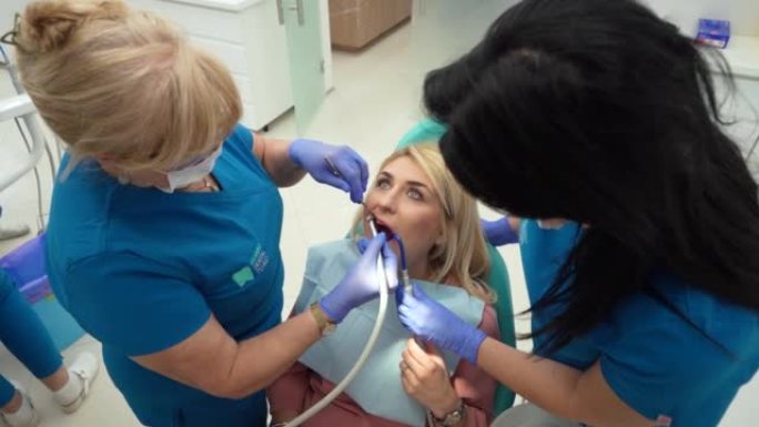 高级女性高加索牙医，对女性患者进行口腔检查