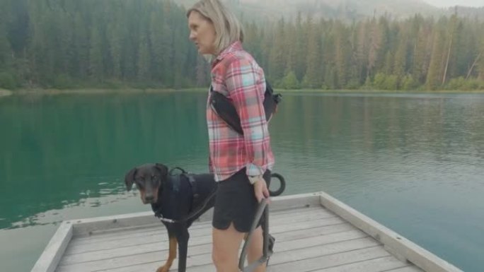与一名妇女和皮带狗一起观看山中的湖泊