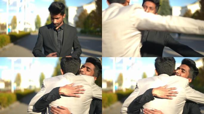 阳光明媚的户外，年轻的中东男子拥抱朋友在城市街道上遇见盖伊。快乐成功的朋友拥抱微笑的肖像。生活方式和