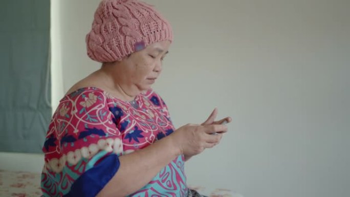 患有癌症的高级女性在家中使用智能手机