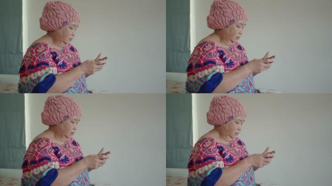 患有癌症的高级女性在家中使用智能手机