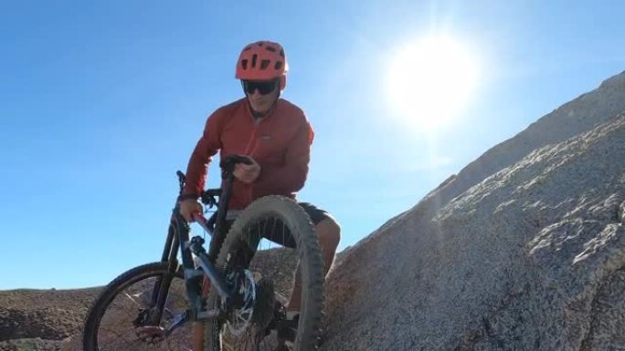男性山地自行车手从山顶下降陡峭的岩石