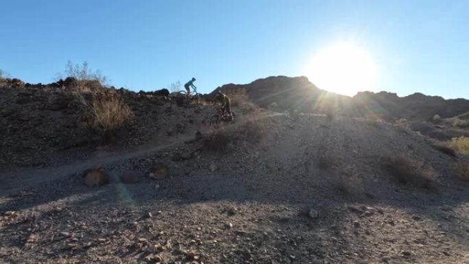 男性山地自行车手在崎terrain的地形上沿着沙漠小路行驶
