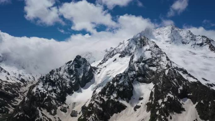 空中飞行穿过山云，飞越美丽的白雪皑皑的山峰和冰川。