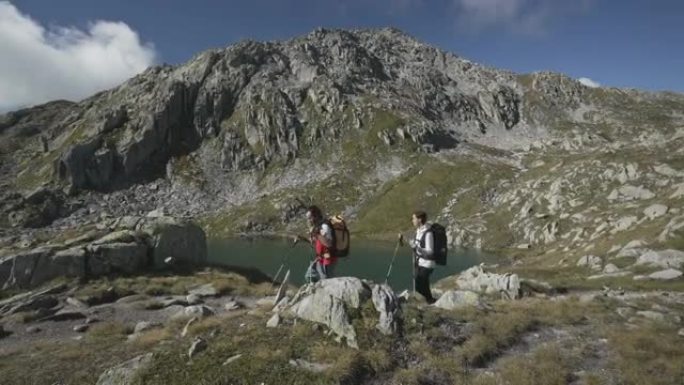 一个男人和狗在山上的一个湖边徒步旅行的照片