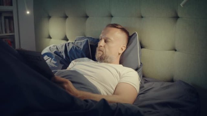 躺在床上的男人因失眠而无法入睡。阅读杂志