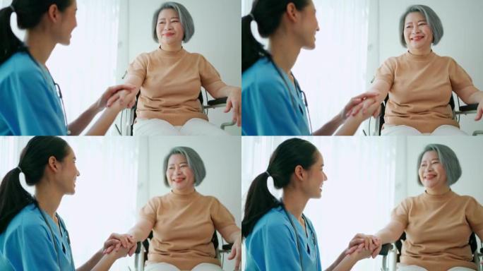 亚洲自信的女医生握着坐在轮椅上的女老年妇女的抚摸手。给予支持，微笑鼓励病人。医疗保险、医疗保健和舒适