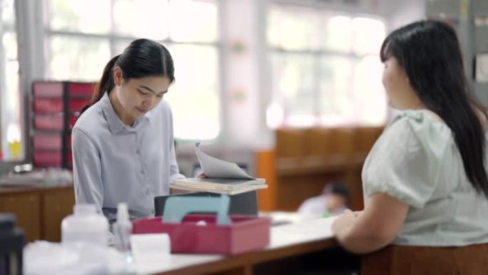 在亚洲的大学图书馆，亚洲女性正在通过图书馆的平板电脑搜索互联网。