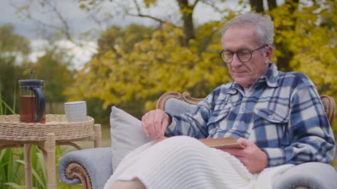 生病的老人病人在外面的椅子上看书