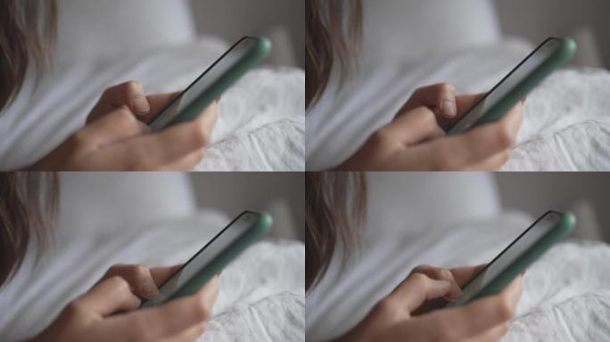 一名年轻女子在床上使用电话的细节照片