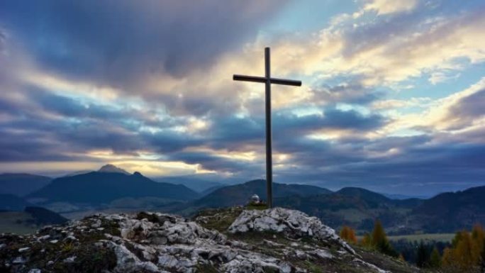 日落时岩石上的基督十字架，彩云。