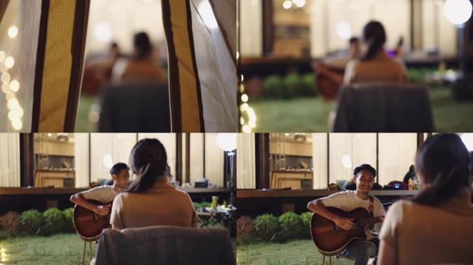 年轻的亚洲夫妇作为音乐家在户外露营时一起弹吉他。