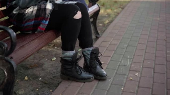 面目全非的无家可归的女人在公园里为坐在长椅上的鸟扔面包。无屋白人年轻女士的腿在户外小巷里喂鸽子。