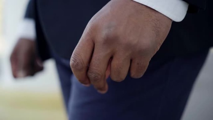 非裔美国男性手弹指的特写。穿着西装的面目全非的年轻人站在户外。焦虑和生活方式。