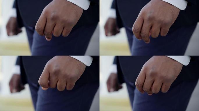 非裔美国男性手弹指的特写。穿着西装的面目全非的年轻人站在户外。焦虑和生活方式。
