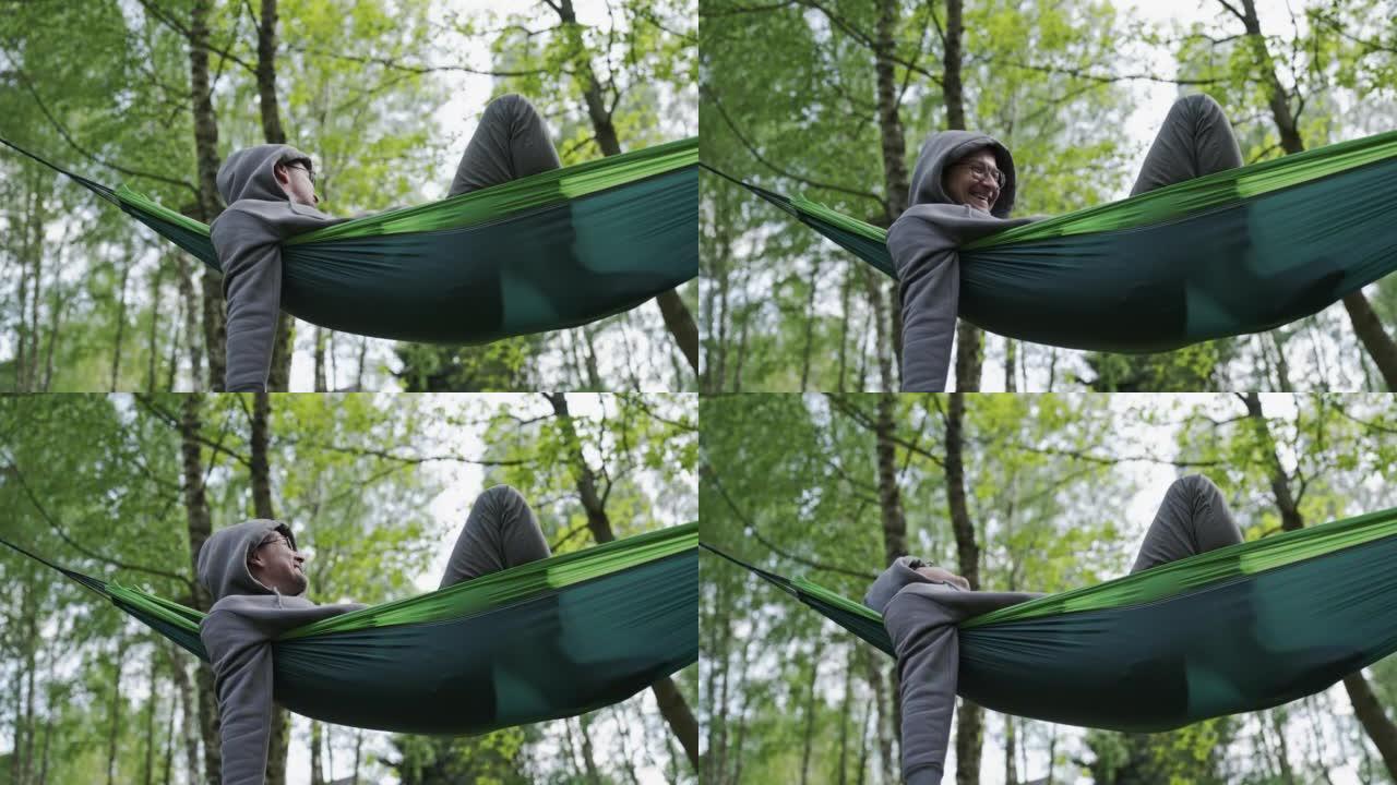 男人在树林里的吊床上放松。充分享受大自然