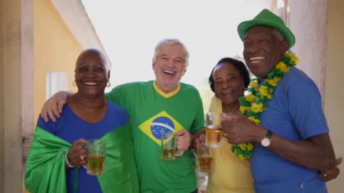 老人朋友穿着巴西衣服在家喝啤酒的肖像